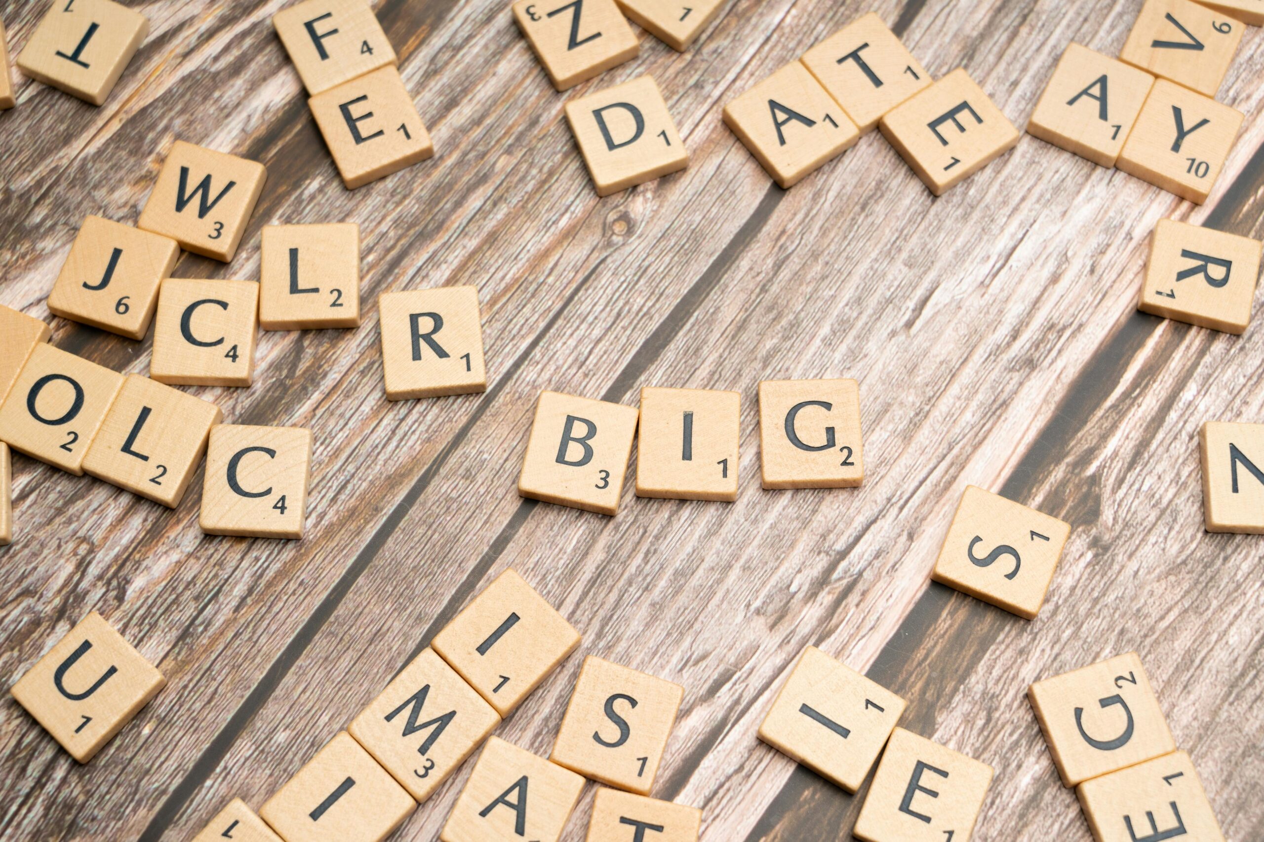 Scattered wooden letter tiles on a textured wooden table surface for creative word play.