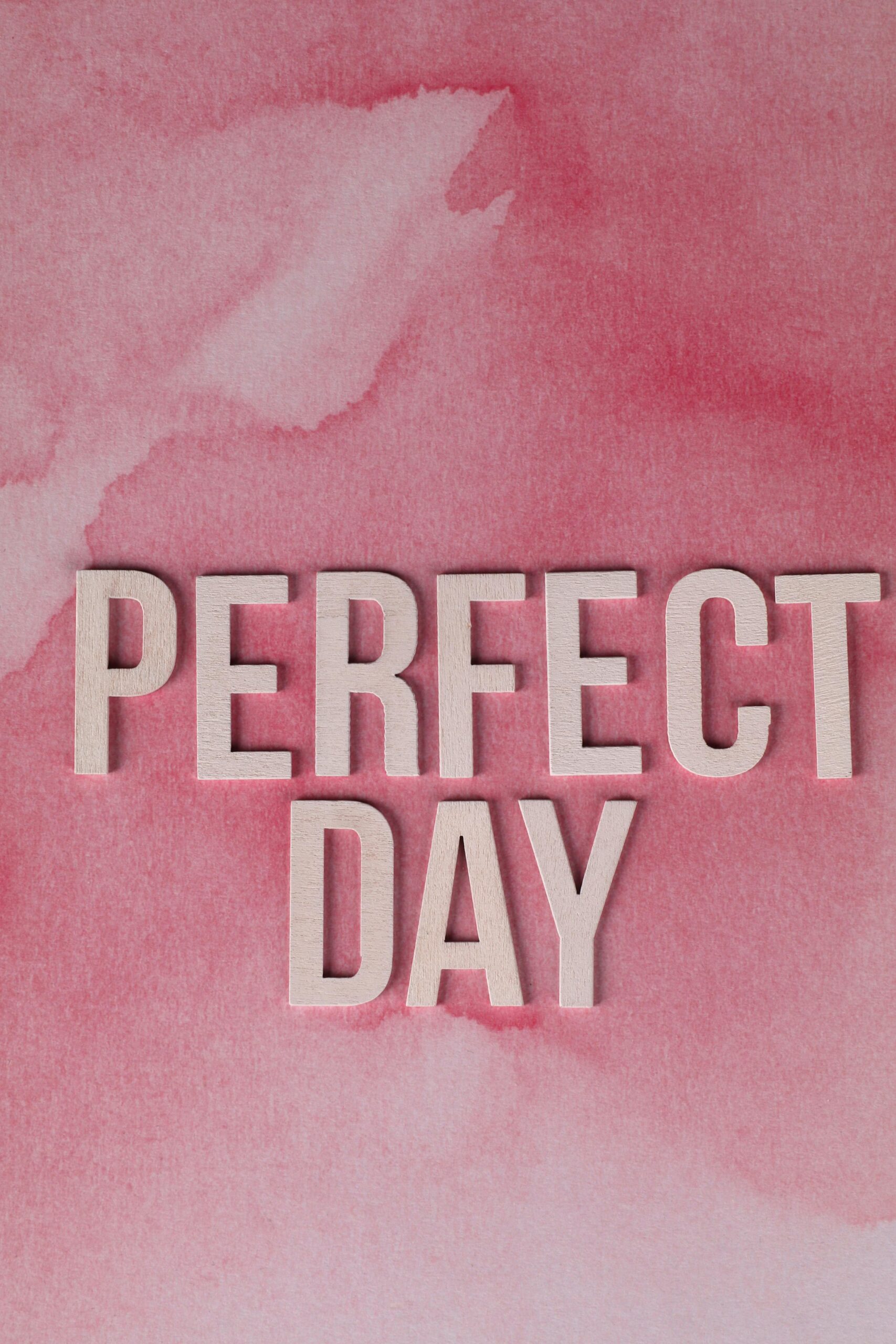 Text 'Perfect Day' on a pink watercolor background, ideal for inspirational design.